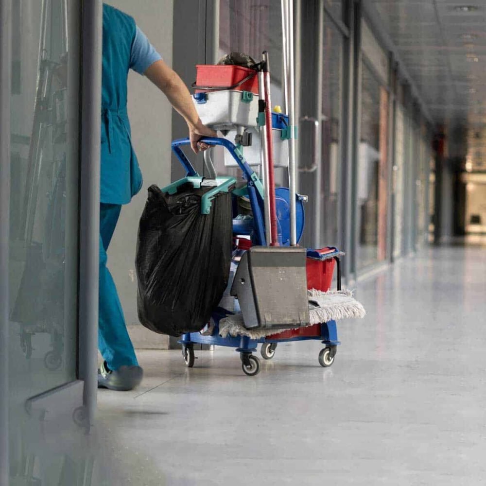Janitorial services professional disinfecting high-touch office surfaces with organized cleaning tools nearby